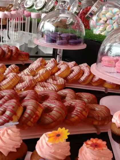 A dessert table featuring rows of beautifully decorated donuts and cupcakes. A sweet spread like this is a centerpiece in itself.