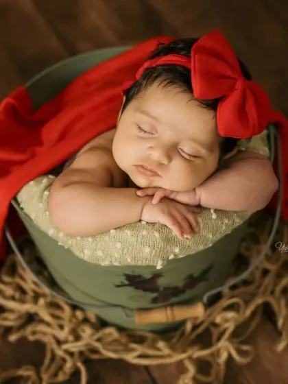 A simpler composition focusing on the baby sleeping in the bucket, with a rustic rope detail in the foreground.
