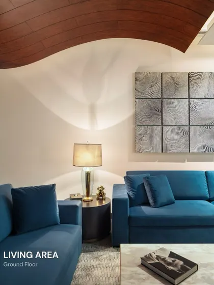 The living area of our Vasant Vihar residence features a dramatic curved wooden ceiling element and bold blue sofas. This space showcases our ability to play with form and color to create a dynamic yet inviting atmosphere.