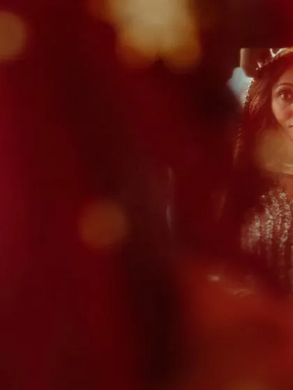 An artistic shot of a bride through a red veil, creating a soft and romantic feel. The focus is on her expression and the beautiful color of the fabric.