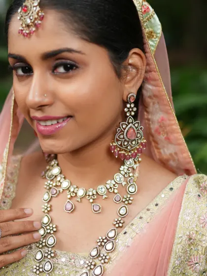 A beautiful close-up of the bride, showcasing the intricate details of the Polki necklace and the stunning earrings with pink stone drops.