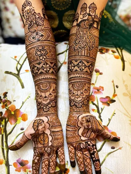 A unique take on portrait mehandi, with the bride and groom figures placed on the thumbs. The arms feature peacock and jharokha designs.