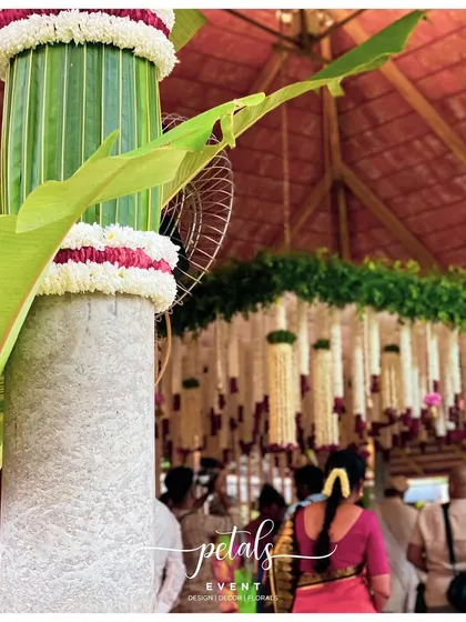 A close-up of a pillar decorated with coconut leaves and flowers, a classic element of South Indian decor.