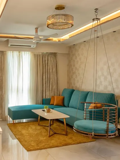 A wide shot of the teal and orange living room, showing the elegant false ceiling with cove lighting and a statement chandelier.