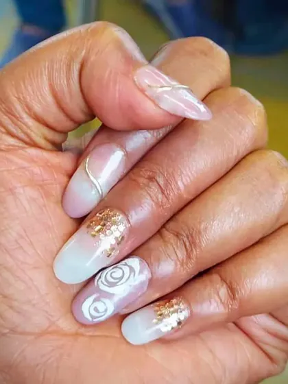 An elegant nail design with a milky white base, gold foil, and delicate swirl patterns. This is a sophisticated look that is very popular with clients.