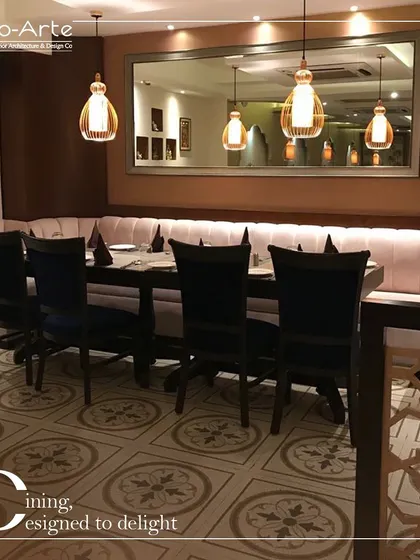 Dining designed to delight at Café Hera Fehri. This seating arrangement combines a long, comfortable banquette with elegant chairs and patterned floor tiles, creating a space that is both contemporary and timeless.