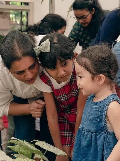 A teacher helps children get a closer look at the fishbowl, fostering a gentle and respectful interaction with animals.