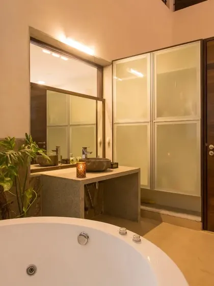 A closer look at the indoor-outdoor bathroom, showing the custom concrete vanity, stone washbasin, and translucent glass wardrobes, all adjacent to the open-to-sky tree court.