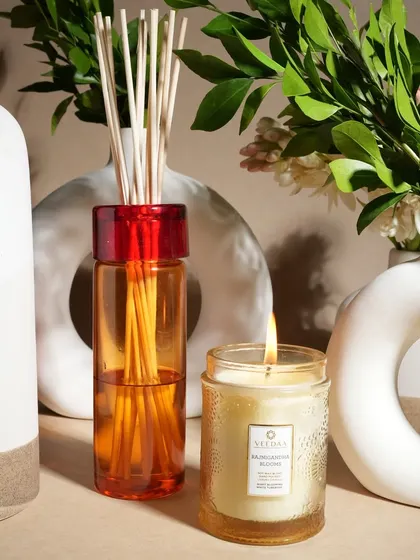 A modern decor setting featuring our Rajnigandha Blooms candle and reed diffuser. The combination of the warm candle glow and the constant scent from the diffuser creates a layered and inviting ambiance.