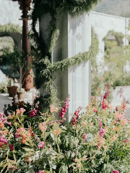 A close-up of the floral and greenery details from Nithya and Payton's wedding. We love layering different textures and colors, like these soft pink snapdragons against the cool stone pillar wrapped in delicate vines.