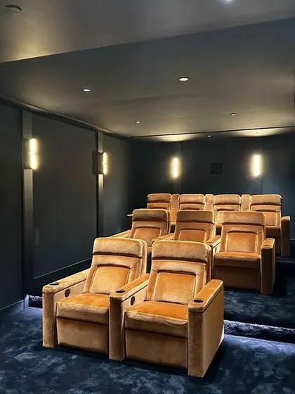 This theater uses a rich, velvety texture on the chairs and a deep blue carpet to create a sense of subtle luxury. The tiered seating ensures everyone has an unobstructed view of the screen.