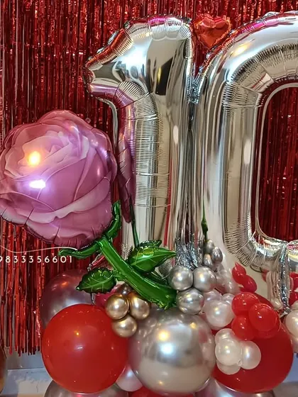 A close-up of the anniversary decor, highlighting the large rose-shaped foil balloon and the metallic number balloons.