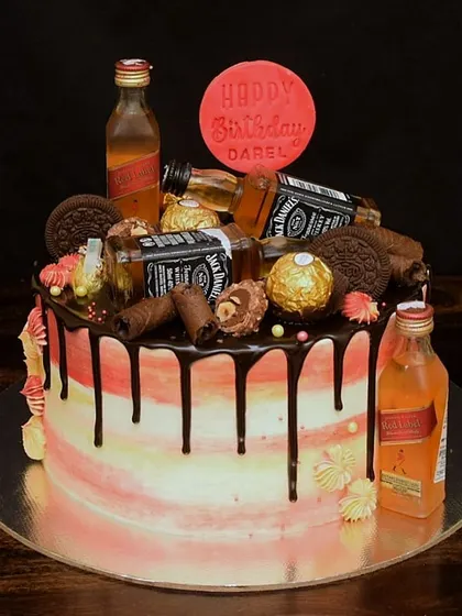This loaded cake features Jack Daniel's and Johnnie Walker miniatures. The sides have a pink and yellow watercolor effect, contrasted with a rich dark chocolate drip for a truly decadent look.