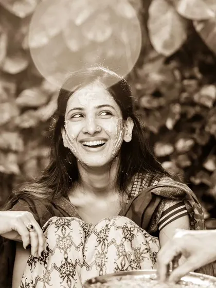 A moment of pure, unscripted laughter during the Haldi. This sepia-toned photo captures the bride sharing a laugh with her friends or family, a perfect candid shot.