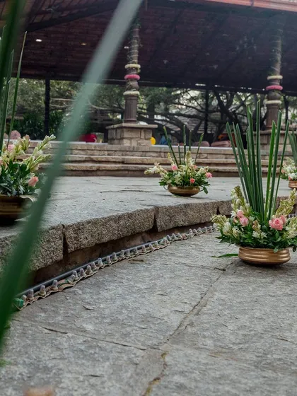 Small floral arrangements in brass pots lining the steps of the venue.