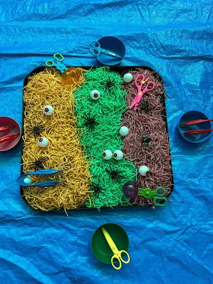 Inspired by Eric Carle, this sensory tray uses colored noodles, googly eyes, and child-safe scissors. It's a wonderful activity for practicing cutting skills and exploring fun textures.
