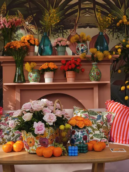 Another view of the mantelpiece, showcasing the rich textures and colors of the floral arrangements and the detailed mural behind.