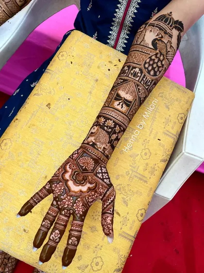 A full-arm bridal design featuring a mix of floral, peacock, and elephant motifs. The pattern flows beautifully from the hand to the elbow.
