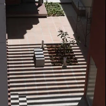 An elevated view of a landscaped courtyard. This perspective shows how the design carves out shaded outdoor rooms, using simple planters and benches to create functional and peaceful breakout zones for the artisans.