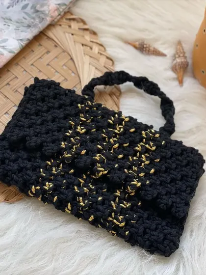Perfect for a party, this black clutch bag has shimmery gold thread woven throughout, creating a subtle sparkle that catches the light beautifully.