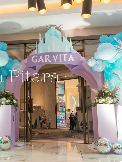 An enchanting entrance to a 'Frozen' themed fourth birthday party. The archway, adorned with balloons in icy shades of blue, purple, and silver, and featuring characters from the movie, welcomes guests into a winter wonderland.