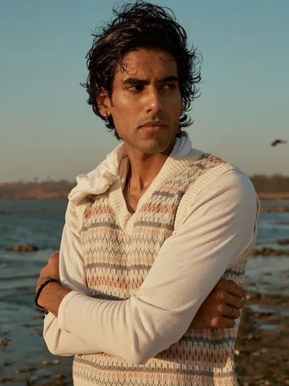 A male model portrait taken at the beach during the golden hour. The warm light and the soft gaze create a calm and soulful image.
