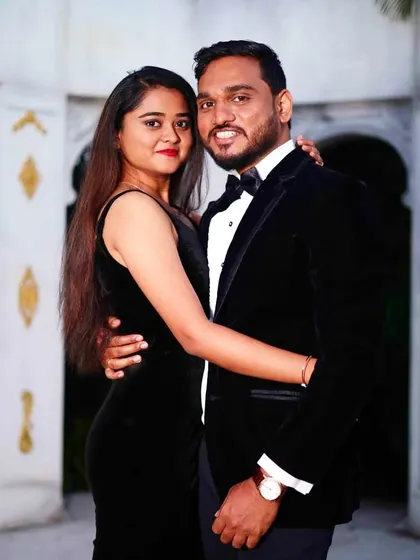 A classic power couple look. She is wearing a sleek black velvet slit gown, and he is in a matching black velvet tuxedo, perfect for a glamorous evening event or photoshoot.