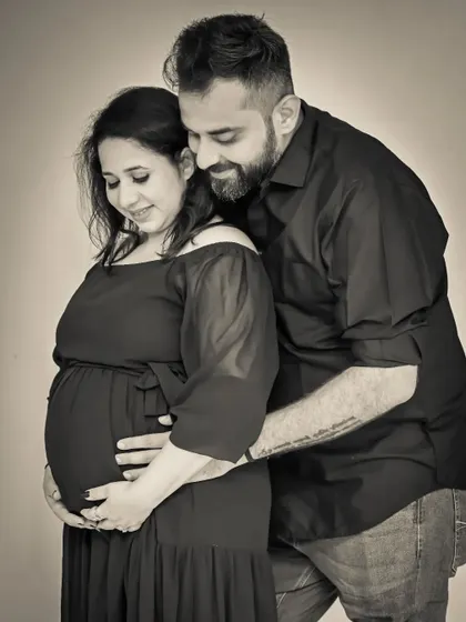A classic black and white studio portrait. The dark background and the couple's embrace create a moody, intimate, and timeless image that focuses purely on their emotion.
