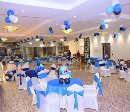 A full view of a banquet hall decorated for a Boss Baby theme. The tables are covered in blue and white linens with matching chair sashes.