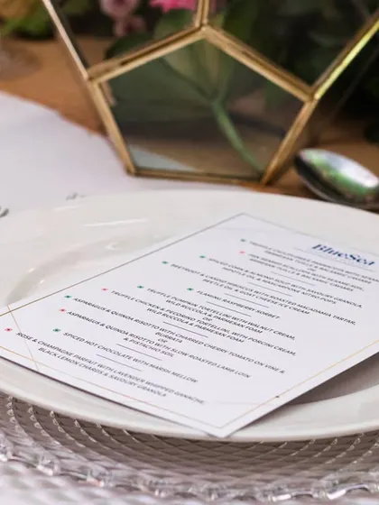 A simple, elegant menu placed on a textured charger plate. This clean and modern approach to table setting reflects a refined aesthetic where every detail is considered.