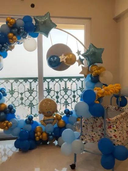 A celestial-themed welcome for a baby boy. This setup features a circular frame decorated with a blue, gold, and white balloon arch, complete with star-shaped foil balloons.