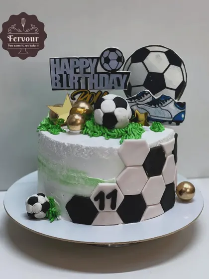 A football-themed cake with a clean design, featuring a soccer ball pattern on the sides and various toppers. This is a great option for a stylish sports-themed party.