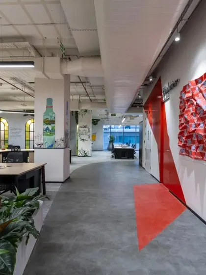 In this hallway at AbInbev, we used bold graphics and a 3D fabric sculpture to create visual interest. The red arrow on the floor is a playful wayfinding element that guides people through the space, while the art on the walls tells the brand's story.