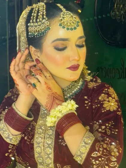 A beautiful candid moment of a Nikkah bride. Her makeup features a soft, dewy base with a hint of blush, paired with a deep maroon lip and smoky eyes, perfectly complementing her velvet outfit.