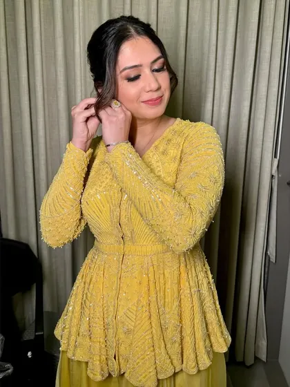 A close-up of this festive Diwali look. The makeup is glowing, with a soft smokey eye that complements her yellow outfit.