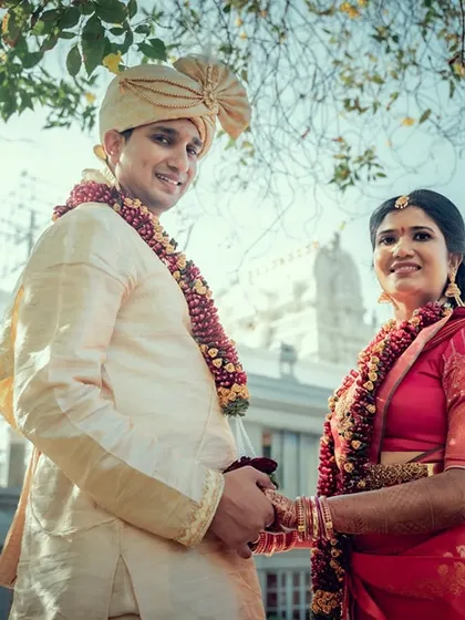 A low-angle shot of a couple standing before a temple, creating a grand and respectful portrait that honors their traditions.