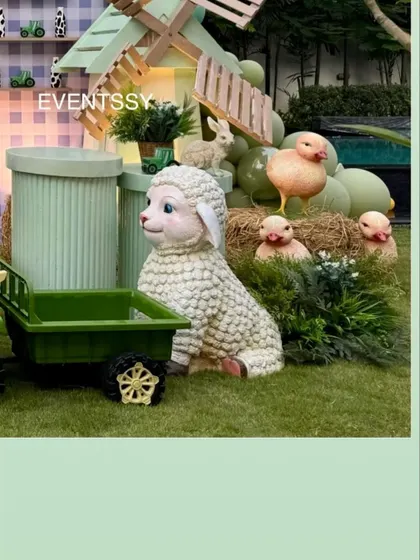 A fluffy sheep prop surrounded by little chicks on hay, adding to the adorable farm scene.