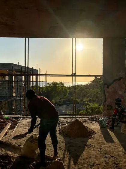 Workers are silhouetted against the setting sun over the ocean at our Zanzibar site. The construction process is timed to the rhythm of the day, with the views providing constant inspiration.