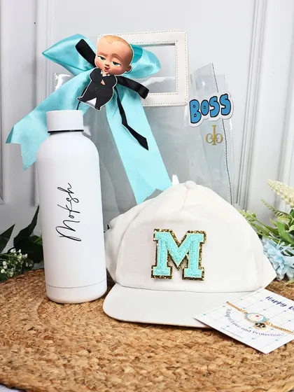 The "Boss Baby" Rakhi hamper is perfect for your brother. It includes a personalized water bottle, a custom initial cap, and a rakhi, all presented on a rustic jute mat.