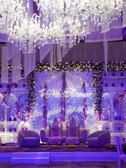A wider view of the grand purple and silver stage. The ceiling is adorned with white fabric panels and crystal chandeliers, creating a sense of scale and opulence.
