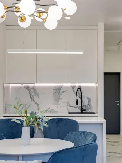 This view shows the dining area opening into a sleek kitchen with a marble backsplash, creating a cohesive and stylish open-plan space.