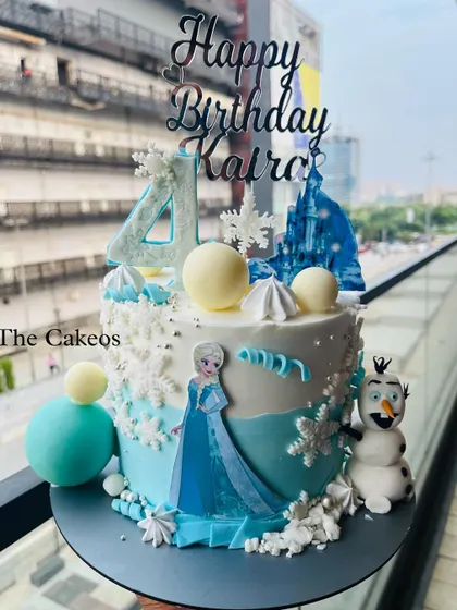 A close-up view of the Frozen themed cake, showing the details of the edible snowflakes, chocolate spheres, and the Elsa and Olaf figures.