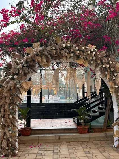A beautiful boho-themed entrance arch using dried pampas grass, macrame hangings, and white florals for a soft, rustic, and chic look.