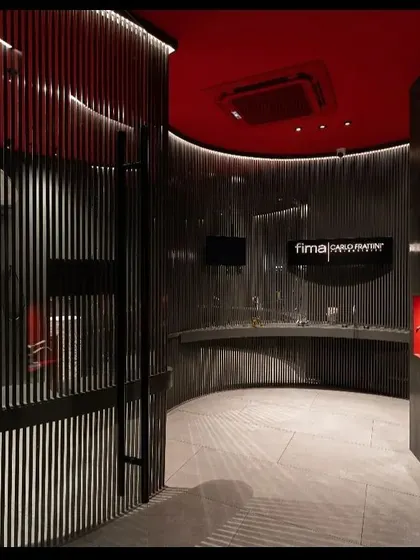 Another perspective of the Fima studio, highlighting how the curved architectural elements are accentuated with light. The design uses darkness as a canvas, with light carefully painted on to guide the eye and feature the displayed products in an artistic, gallery-like setting.