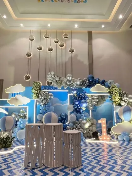 A "sky and clouds" themed first birthday with a blue backdrop, cloud cutouts, and a crescent moon prop.