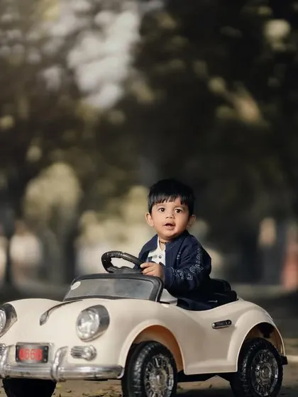 A cool little driver ready for the open road. The vintage car and wooded path give this photo a timeless, adventurous feel.
