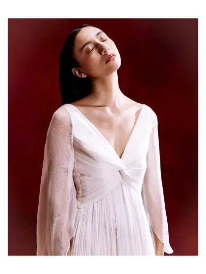 A study in quiet elegance, this white dress features a draped V-neckline and flowing bell sleeves. The soft, ethereal fabric makes it a beautifully understated choice for any special occasion.