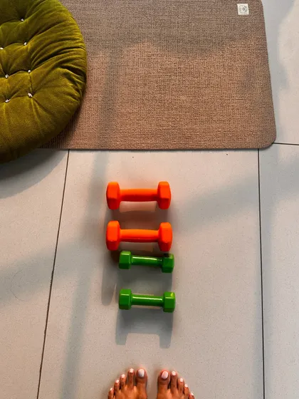 A view from the mat, showing a set of colorful dumbbells ready for a yoga with weights session.