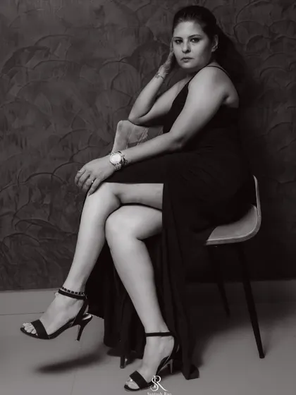 A full seated portrait in the black gown, showing how it drapes elegantly. The simplicity of the dress allows the focus to be on the person wearing it.