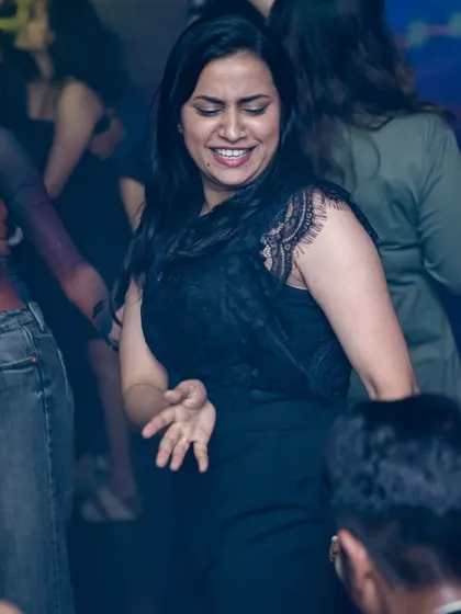 A woman grooving to the beat, completely in her element. The dance floor is a space for freedom and expression.
